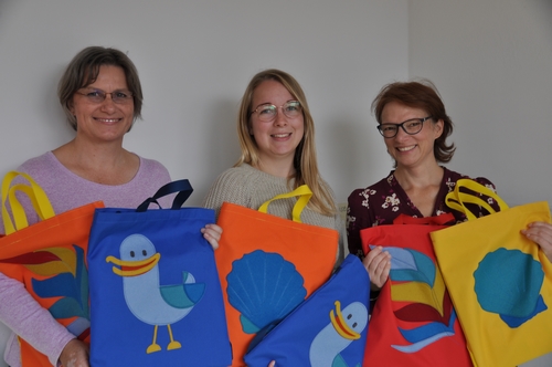 Pr&auml;sentieren die bunten Rucks&auml;cke mit Kinderb&uuml;chern (v.l.): Marieluise Kr&ouml;plin-Scheer, Frances Szepan und Dajana Stolz